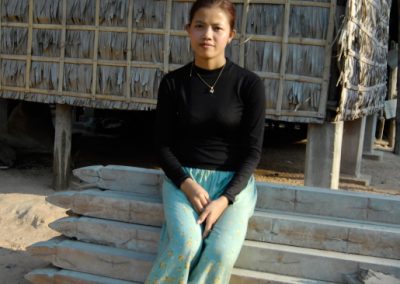 Portrait d'une jeune femme devant sa maison, assise sur des matériaux de construction, village de Sra Srang, province de Siem Reap.