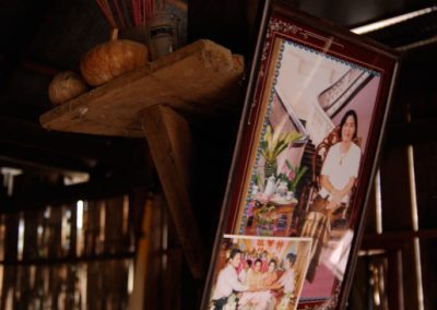 Intérieur d'une maison, photographies de famille encadrées et bâtons d'encens posés autour d'une poutre, province de Kampong Cham.